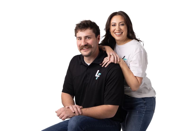 Smiling man and woman posing together, showcasing branded apparel in a studio setting.